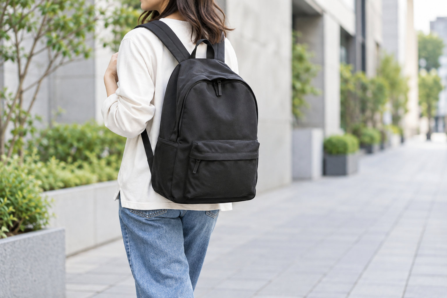 白いトップスとデニムに黒いリュックを合わせた後ろ姿