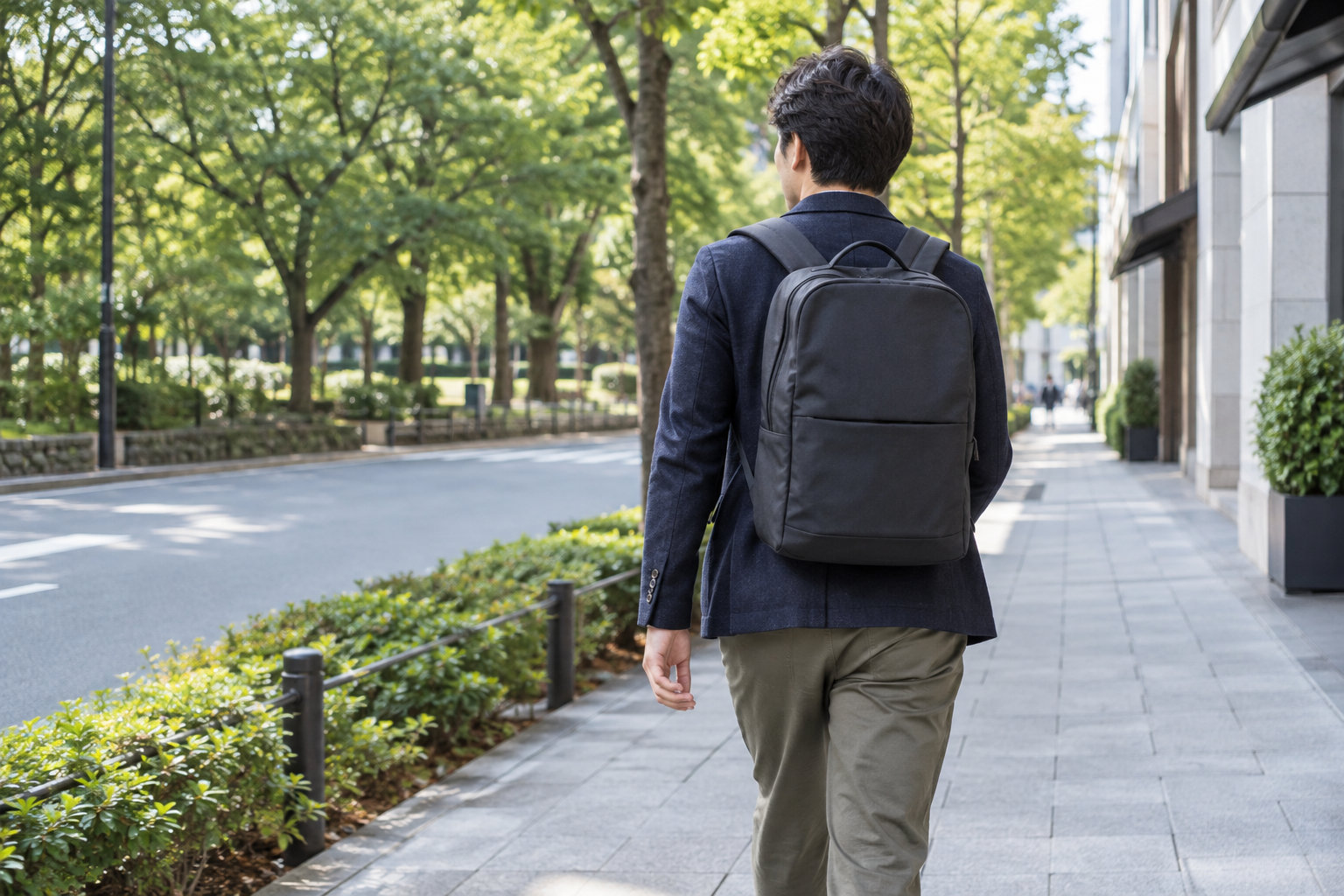 街中で無地のリュックを背負って歩く大人の後ろ姿