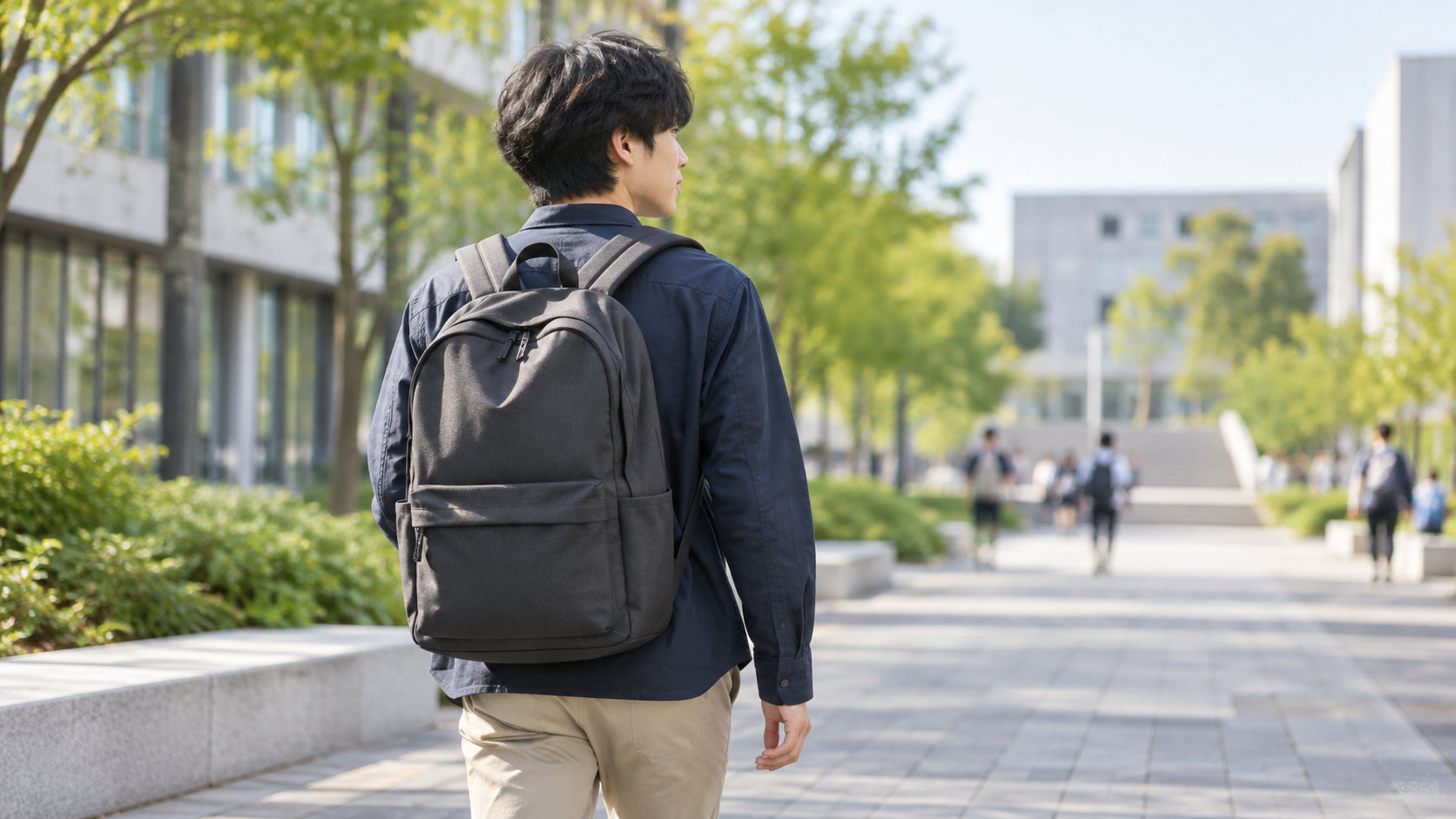 大学生が通学で黒いリュックを背負ってキャンパスを歩く様子